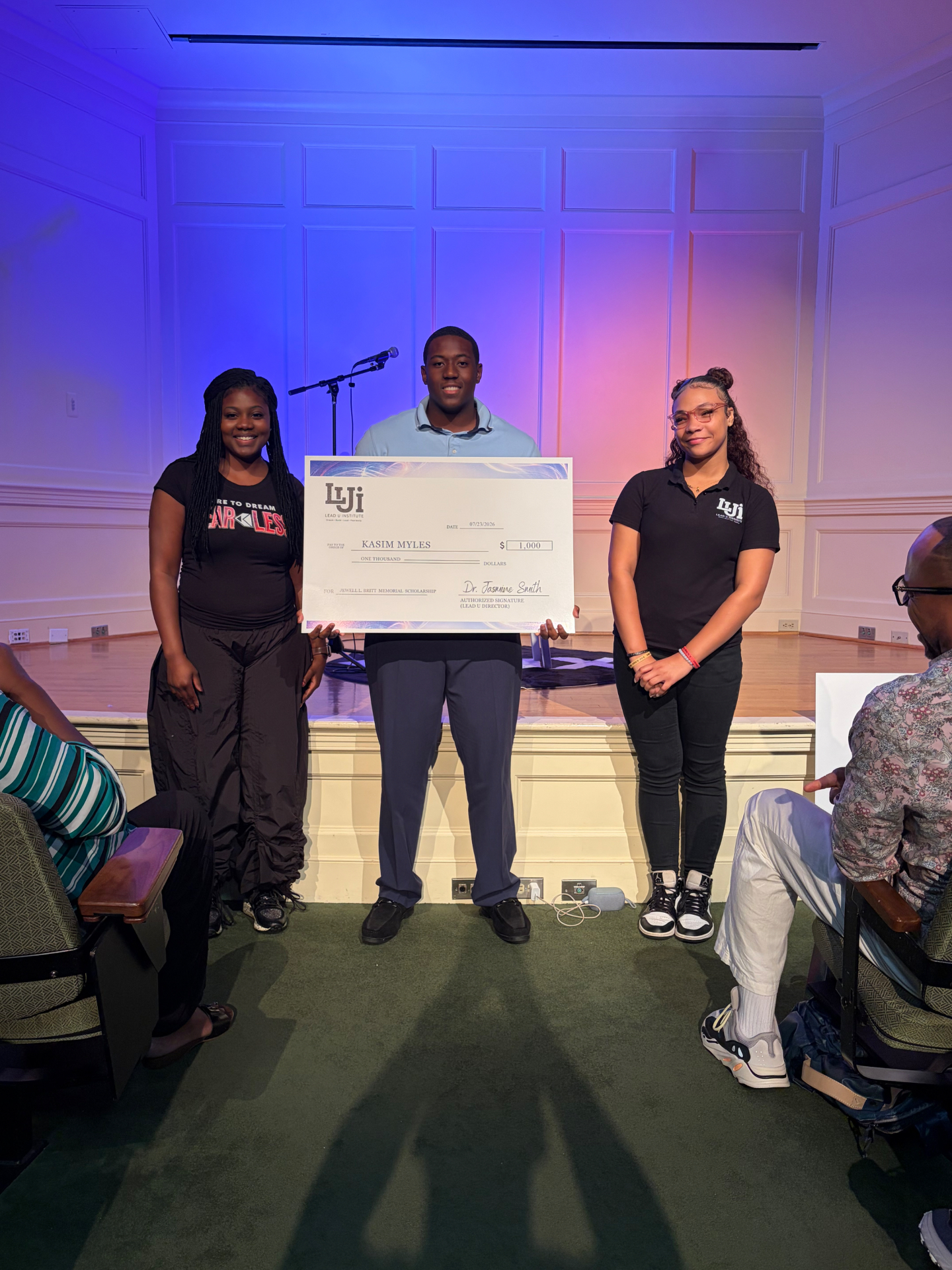 A LEAD U student receiving a $1,000 JLB Memorial Scholarship check on stage at Fearless 1X